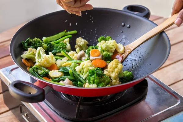 Human hands spreading salt into chinese food capcay — Stock Image Human hands spreading salt into chinese food capcay Stock Image