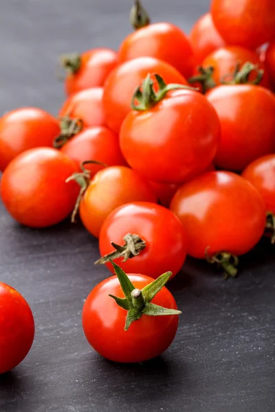 Tomates de cereja em tábua preta de mesa — Fotografia de Stock