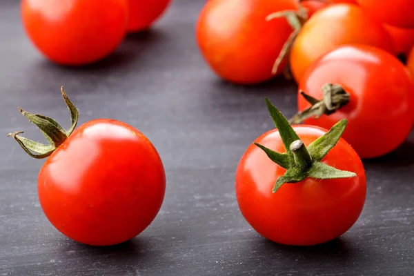 Tomates de cereja em tábua preta de mesa — Fotografia de Stock