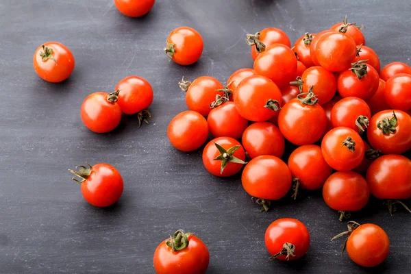 Grupo de tomates cereja em placa preta — Fotografia de Stock