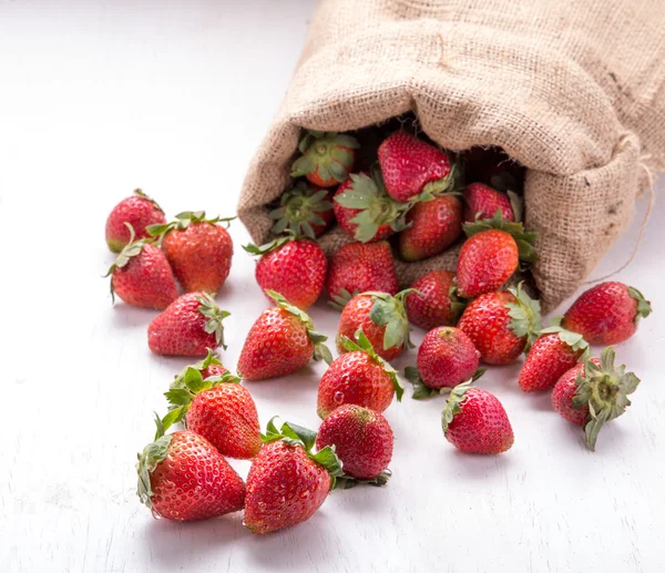 Burlap sack with strawberries spilling out — Stock Photo, Image
