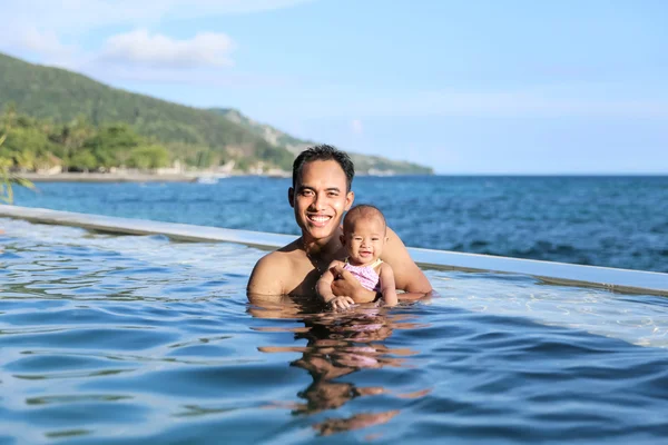 Family with baby having fun in pool — Stock Photo, Image