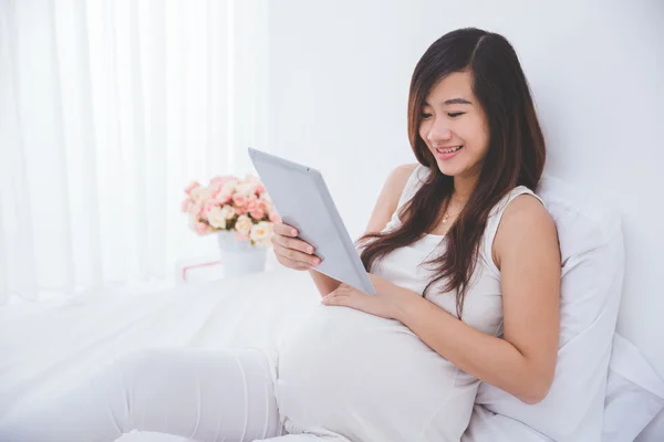 Zwangere vrouw met een tablet pc — Stockfoto