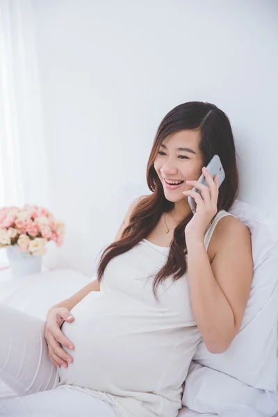 Zwangere Aziatische vrouw praten over de telefoon — Stockfoto
