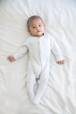 bir yatakta yatarken gülümseyen mutlu bebek 