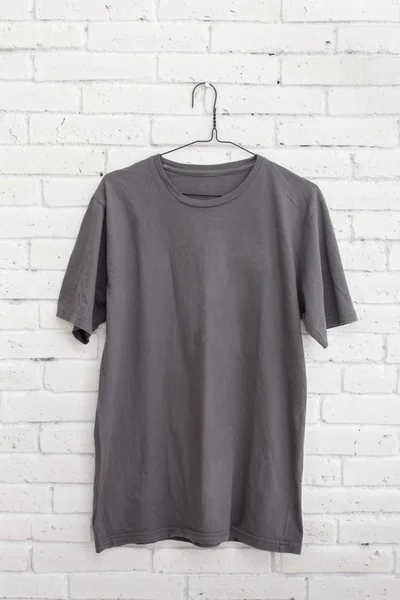 Grey t-shirt hanging on the wall — Stock Photo, Image