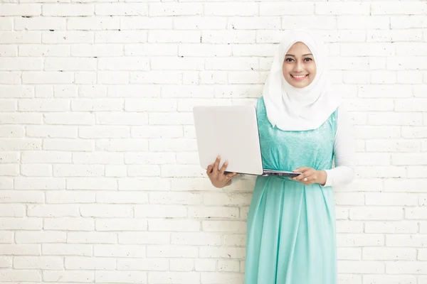 Bir dizüstü bilgisayar tutan hijab giyen Asyalı genç kadın — Stok fotoğraf