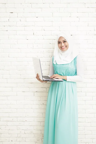 Asiático joven mujer usando hijab de pie mientras sosteniendo un portátil —  Fotos de Stock