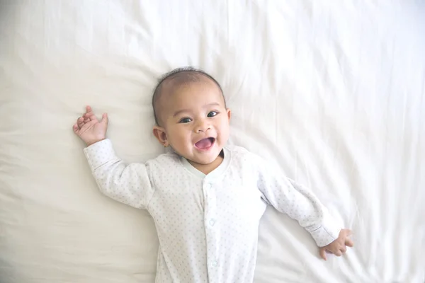 Bebê feliz sorrindo deitado em uma cama — Fotografia de Stock