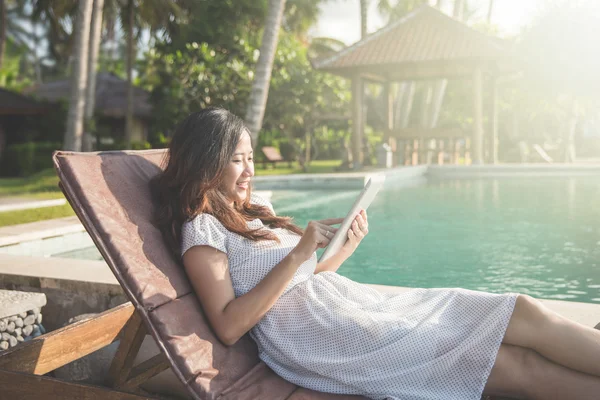 Mujer relajante junto a la piscina y el uso de la tableta — Foto de Stock