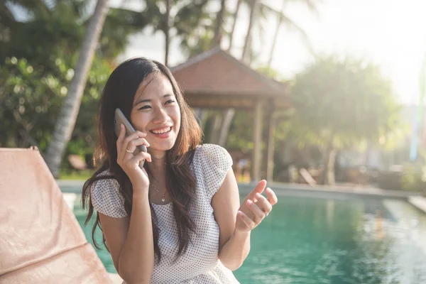 Mulher relaxante ao lado da piscina e chamando usando telefone celular — Fotografia de Stock