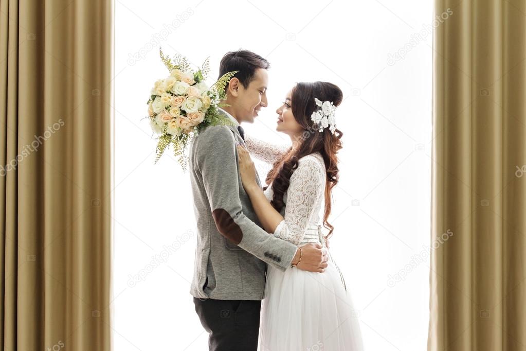 romantic asian newlywed couple embracing each other