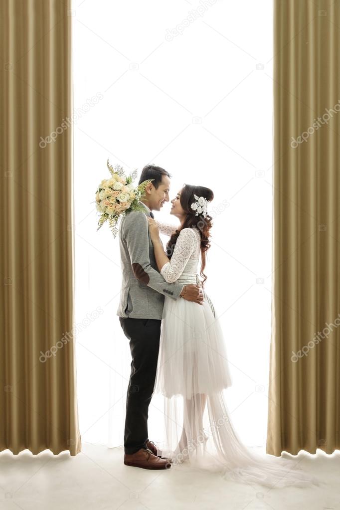 romantic asian newlywed couple embracing each other