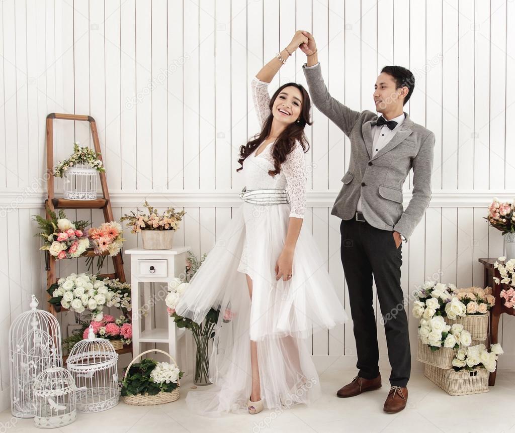 asian newlywed couple dancing at decorated room