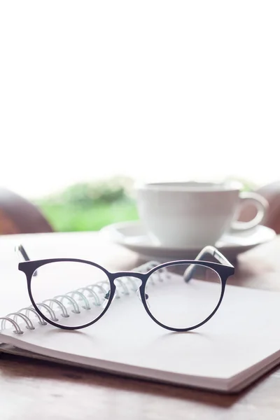 Ouvrir un cahier blanc vierge et des lunettes avec une tasse de café — Photo