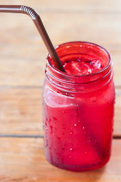 Iced drink in red glass on wooden table — Stock Photo, Image