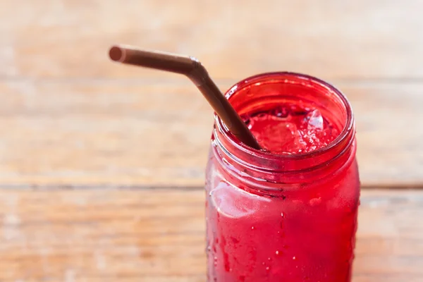 Bebida gelada em vidro vermelho na mesa de madeira — Fotografia de Stock