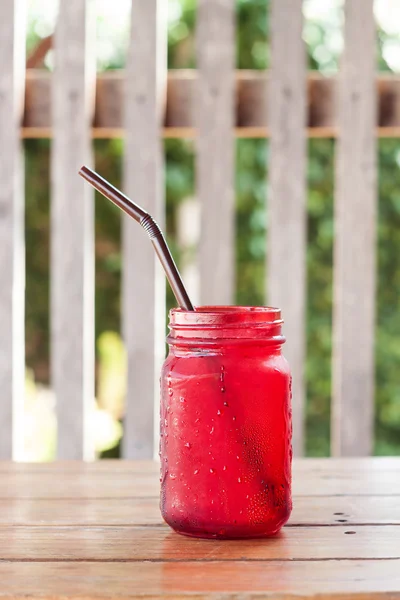 Iced drink in red glass on wooden table — Stock Photo, Image