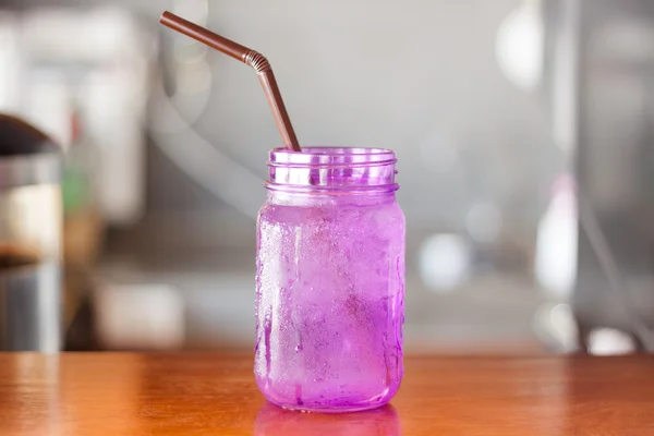 Iced drink in violet glass in coffee shop — Stock Photo, Image