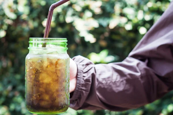 Vrouw hand bedrijf iced soda in groen glas — Stockfoto