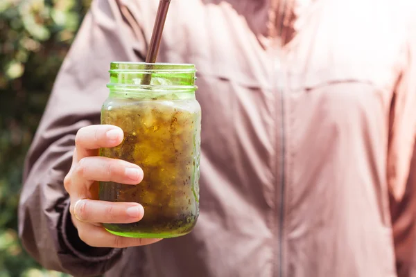 Vrouw hand bedrijf iced soda in groen glas — Stockfoto