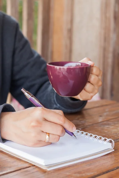 Vrouw hand met pen schrijven op laptop — Stockfoto