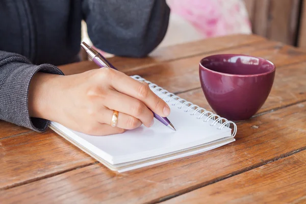 Vrouw hand met pen schrijven op laptop — Stockfoto