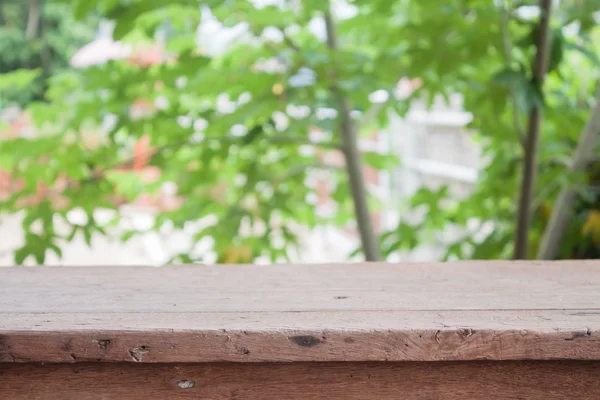 Tavolo in legno vuoto con sfondo foglie verdi sfocate — Foto Stock