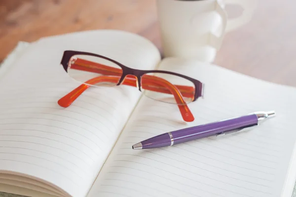 Pen and eyeglasses on notebook — Stock Photo, Image