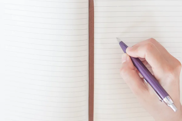 Escritura de la mano de la mujer de primer plano en el cuaderno Imagen De Stock