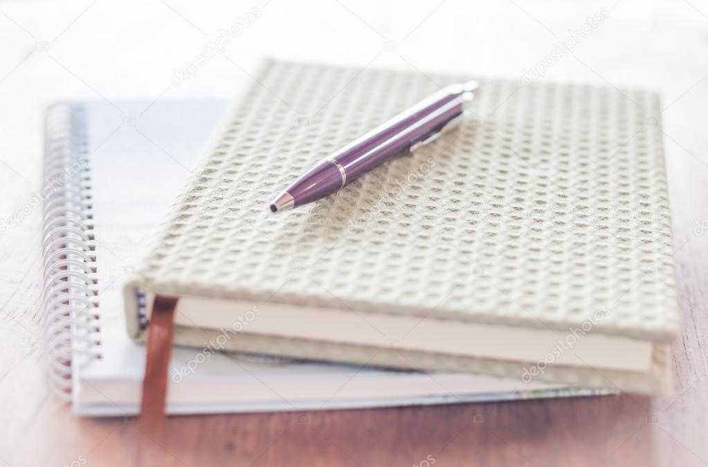 Pen and two of notebooks on wooden table