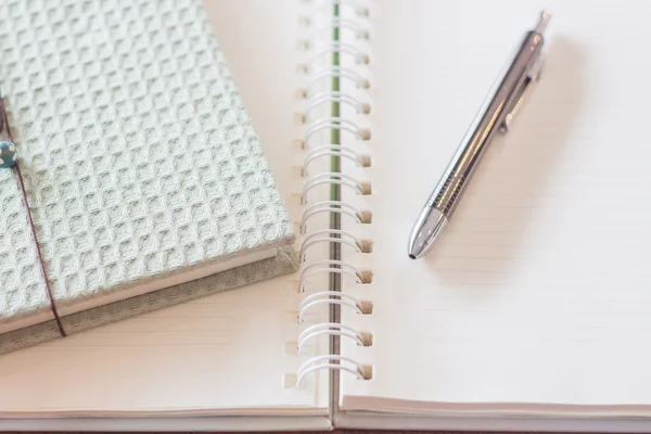 Caneta e caderno de capa verde com caderno em espiral — Fotografia de Stock