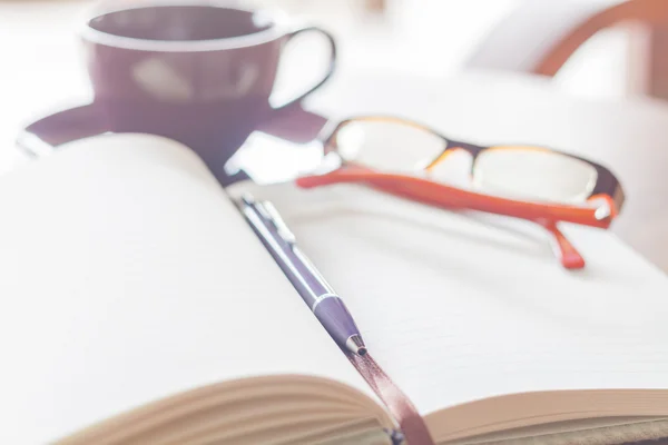 Penna, notebook kaffe kopp och glasögon på tabellen trä — Stockfoto