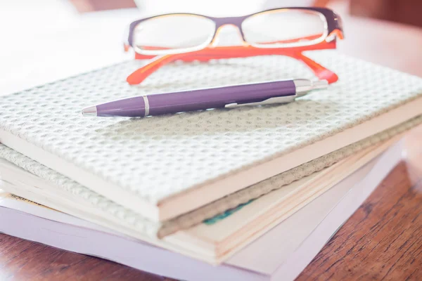 Stift und Brille auf drei Notizbüchern — Stockfoto