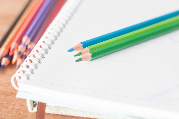 Closeup colorful pencils on spiral notebook and green notebook — Stock Photo, Image