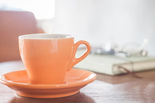 Tazza di caffè arancione con taccuino, penna e occhiali — Foto Stock