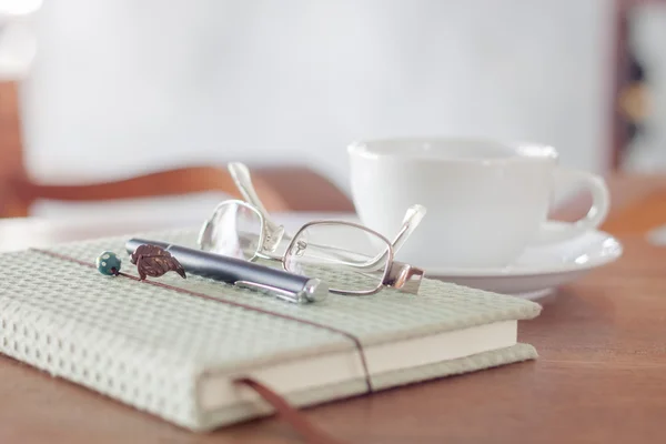 Anteckningsbok med penna, glasögon och vit kaffekopp — Stockfoto