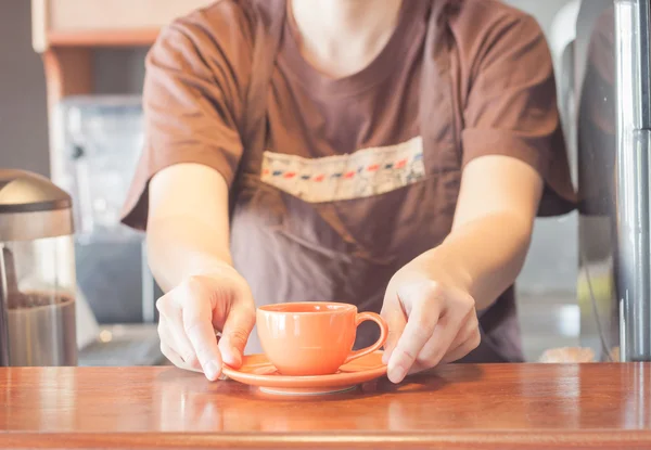 Barista offering mini orange cup of coffee — Stock Photo, Image