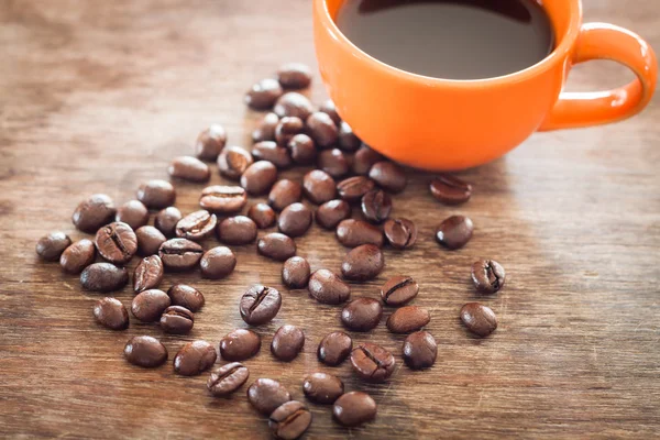 Grains de café avec tasse à café sur table en bois — Photo