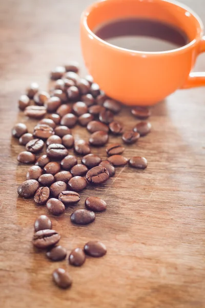 Grãos de café com xícara de café na mesa de madeira — Fotografia de Stock