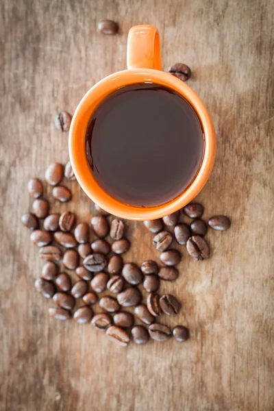 Grãos de café com xícara de café na mesa de madeira — Fotografia de Stock