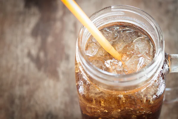 Segelas cola dengan es di atas meja kayu — Stok Foto