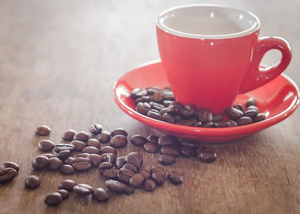 Tasse à café rouge avec grains de café sur table en bois — Photo