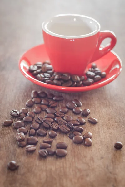 Tasse à café rouge avec grains de café sur table en bois — Photo