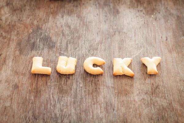Biscoito de alfabeto sorte na mesa de madeira — Fotografia de Stock