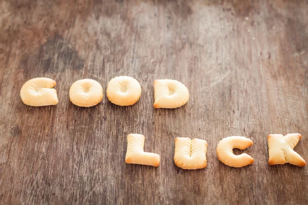 Galleta de buena suerte alfabeto sobre mesa de madera — Foto de Stock