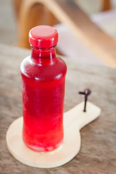 Jarabe rojo en el frasco en plato de madera —  Fotos de Stock