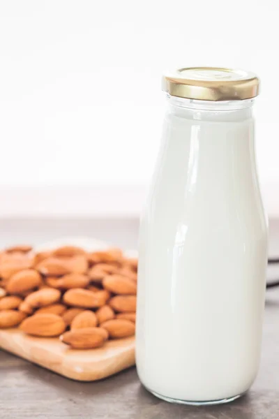 Nueces de almendra en plato de madera con leche — Foto de Stock