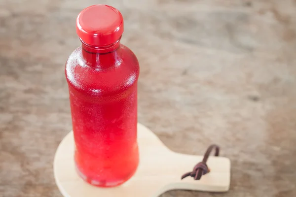 Red syrup in the bottle on wooden plate — Stock Photo, Image