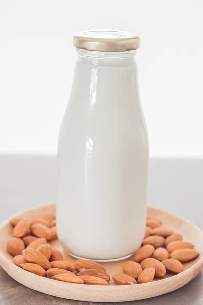 Nueces de almendra en plato de madera con leche — Foto de Stock